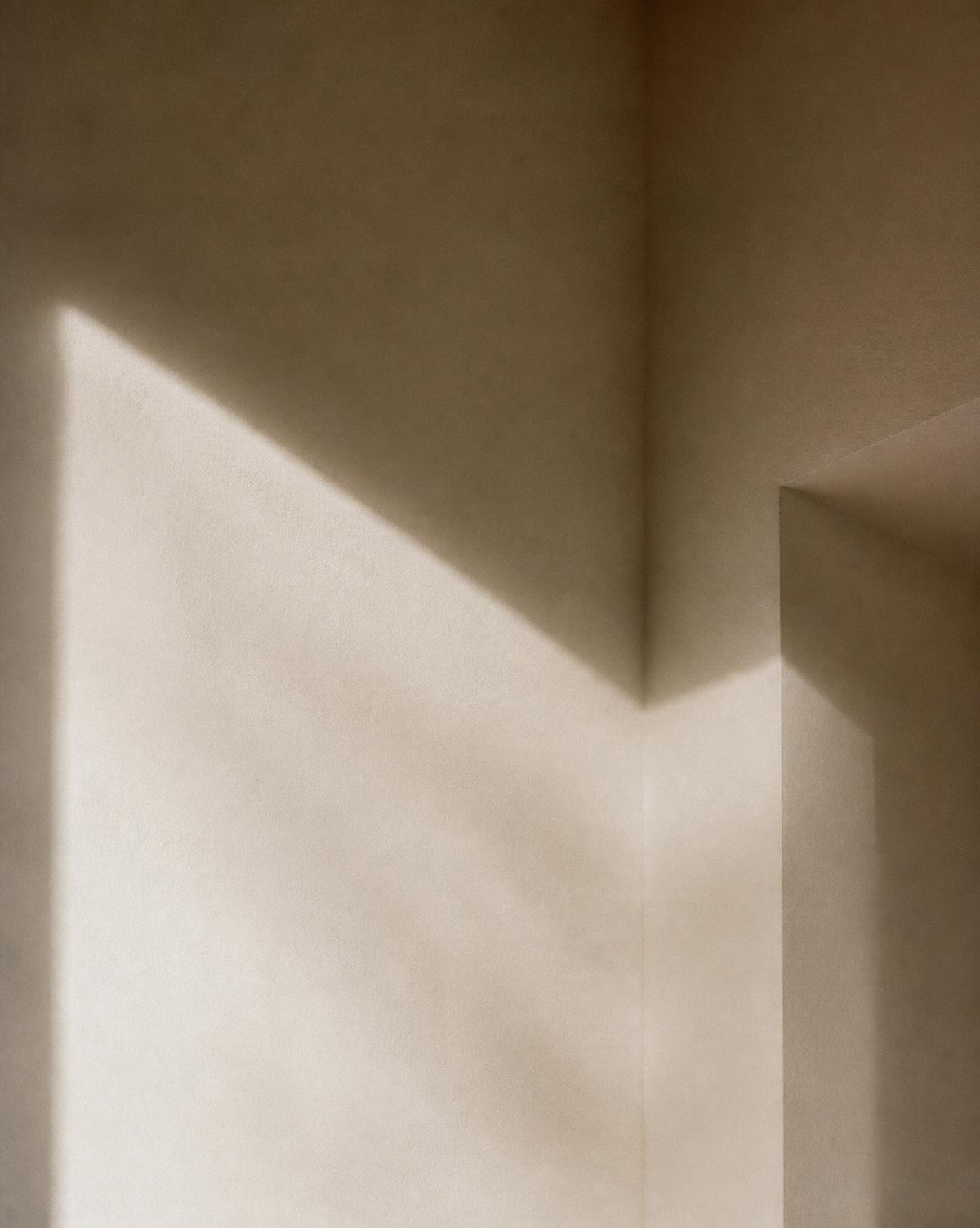 Daylight moving across a pale plaster wall